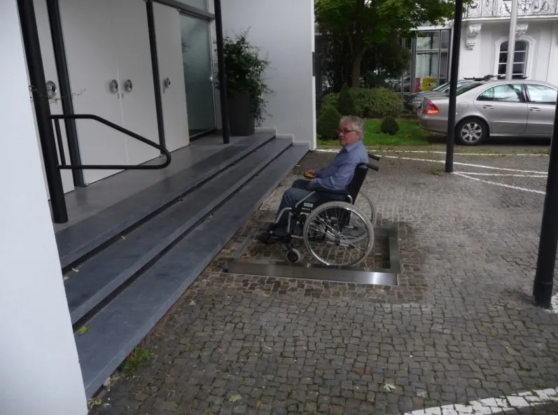 Usuario de silla de ruedas sobre la plataforma en la parte inferior de la escalera.. Acceso a la galería. Abre nueva ventana